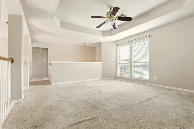 an empty room with windows and ceiling fan