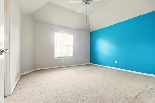 an empty room with a chandelier fan and windows