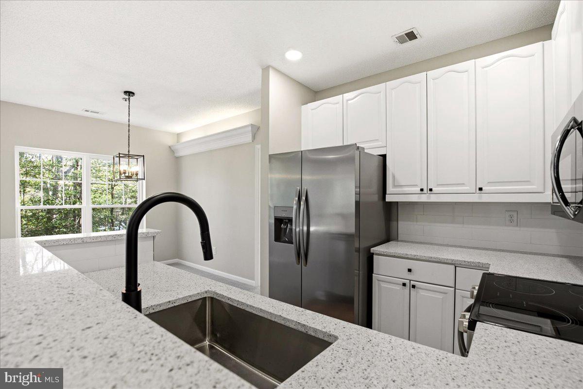 1223 Back Creek Loop, Unit 1223 Solomons, MD 20688 - Photo 19 of 44 a kitchen with stainless steel appliances kitchen island a refrigerator sink and cabinets