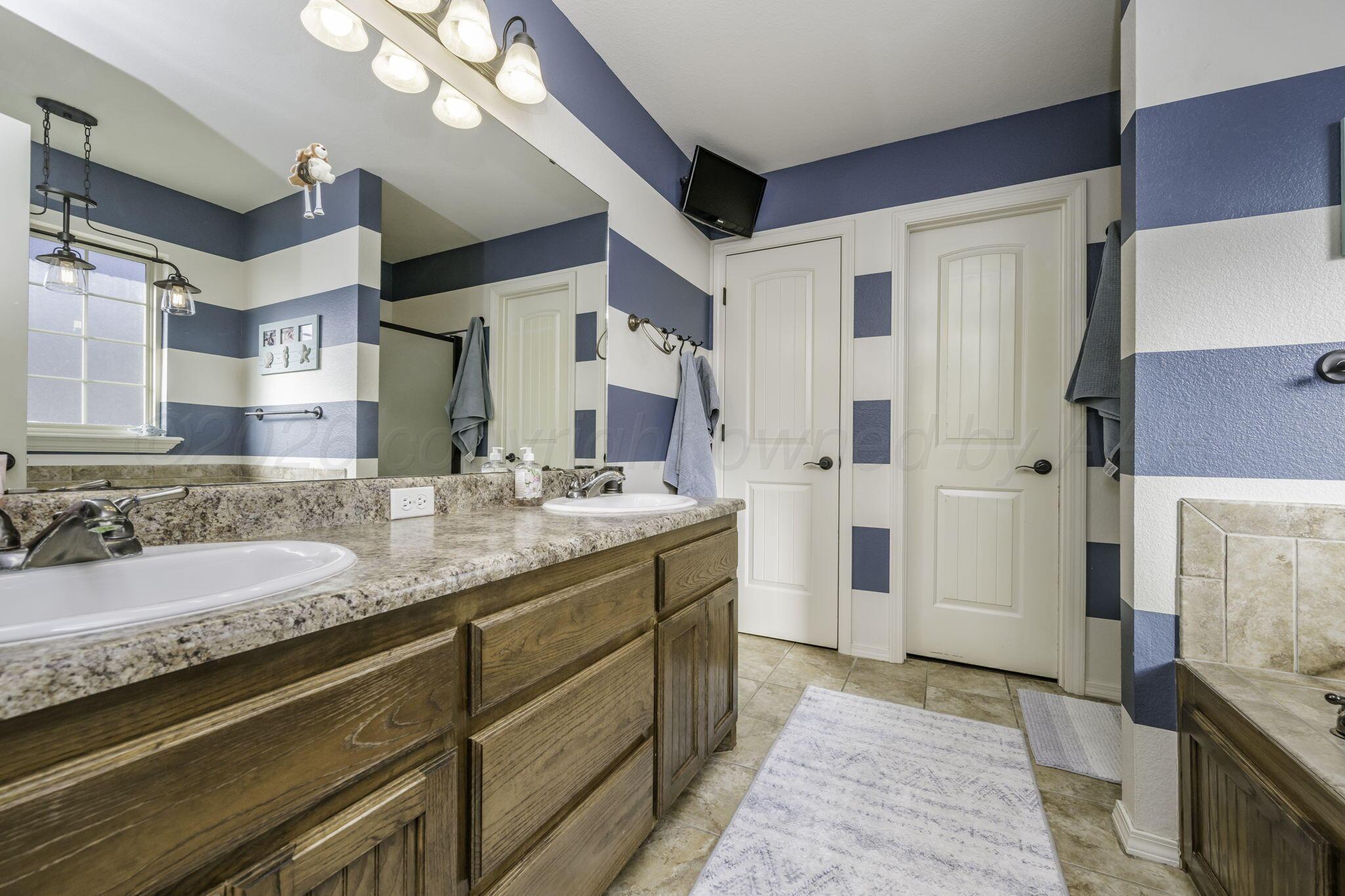 3504 Springfield Avenue Amarillo, TX 79118 - Photo 12 of 23 a bathroom with a granite countertop double vanity sink a mirror and a shower