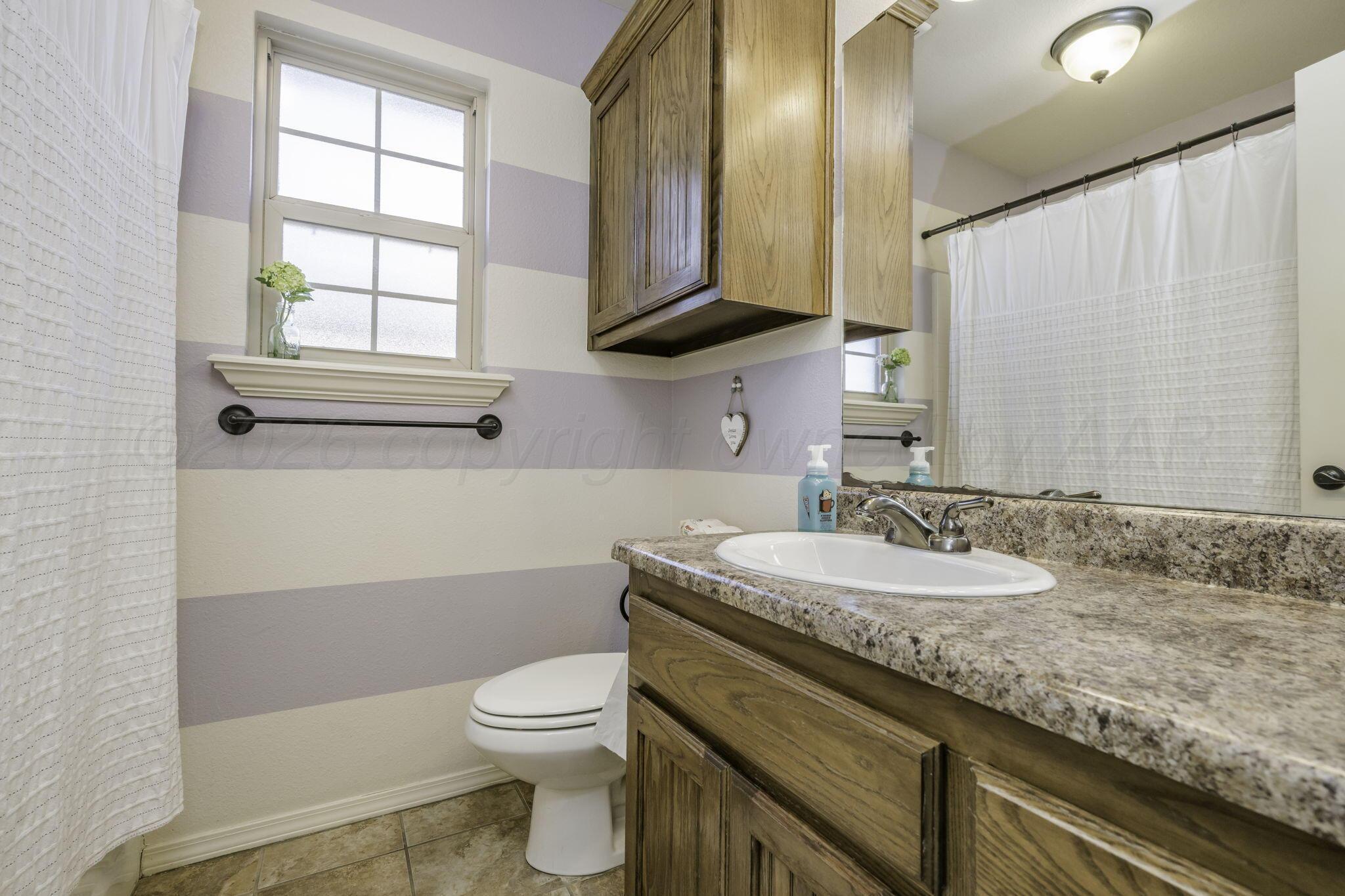 3504 Springfield Avenue Amarillo, TX 79118 - Photo 15 of 23 a bathroom with a granite countertop toilet sink and mirror