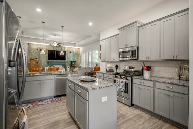 a kitchen with kitchen island granite countertop a sink stainless steel appliances and white cabinets