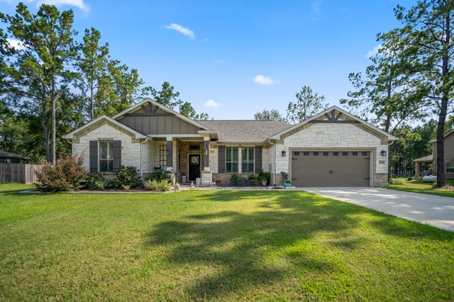 a front view of a house with a garden and trees