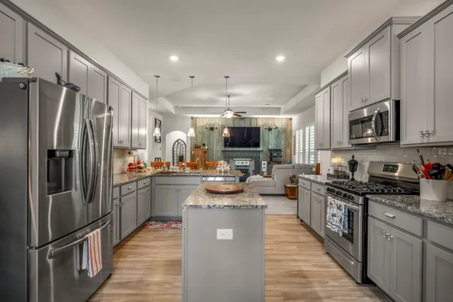 a kitchen with kitchen island granite countertop a sink cabinets and stainless steel appliances