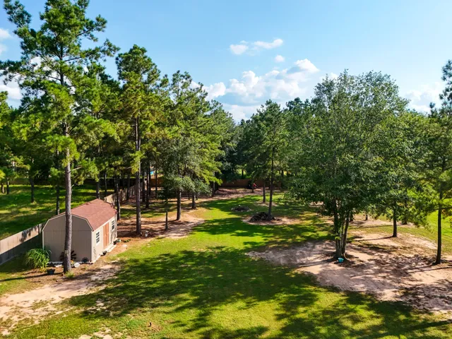a view of a house with a big yard and large trees