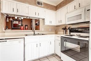 5626 Preston Oaks Road, Unit 39C Dallas, TX 75254 - Photo 30 of 38 Kitchen featuring white appliances, light countertops, white cabinetry, and light tile patterned floors