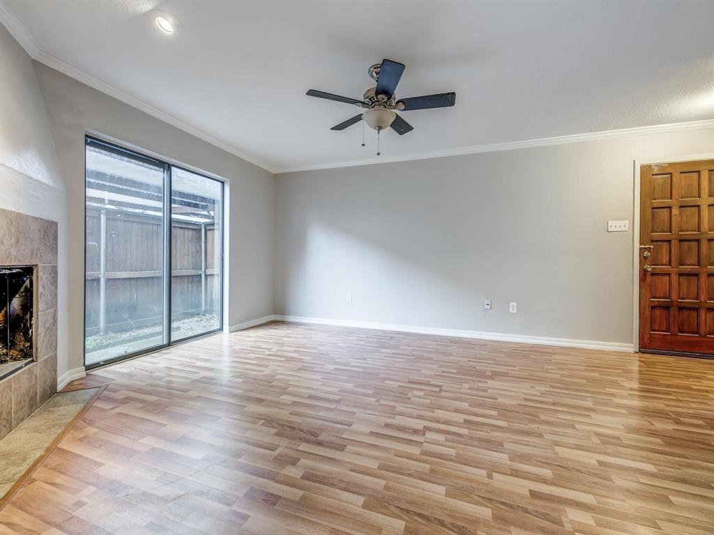 5626 Preston Oaks Road, Unit 39C Dallas, TX 75254 - Photo 5 of 38 Unfurnished living room with ornamental molding, light wood-style flooring, a fireplace, and ceiling fan