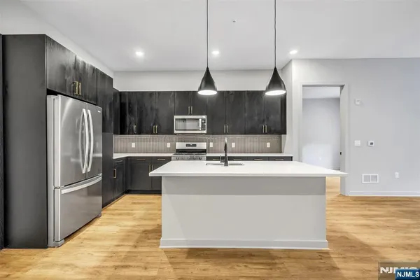 a kitchen with kitchen island a counter top space a sink stainless steel appliances and cabinets