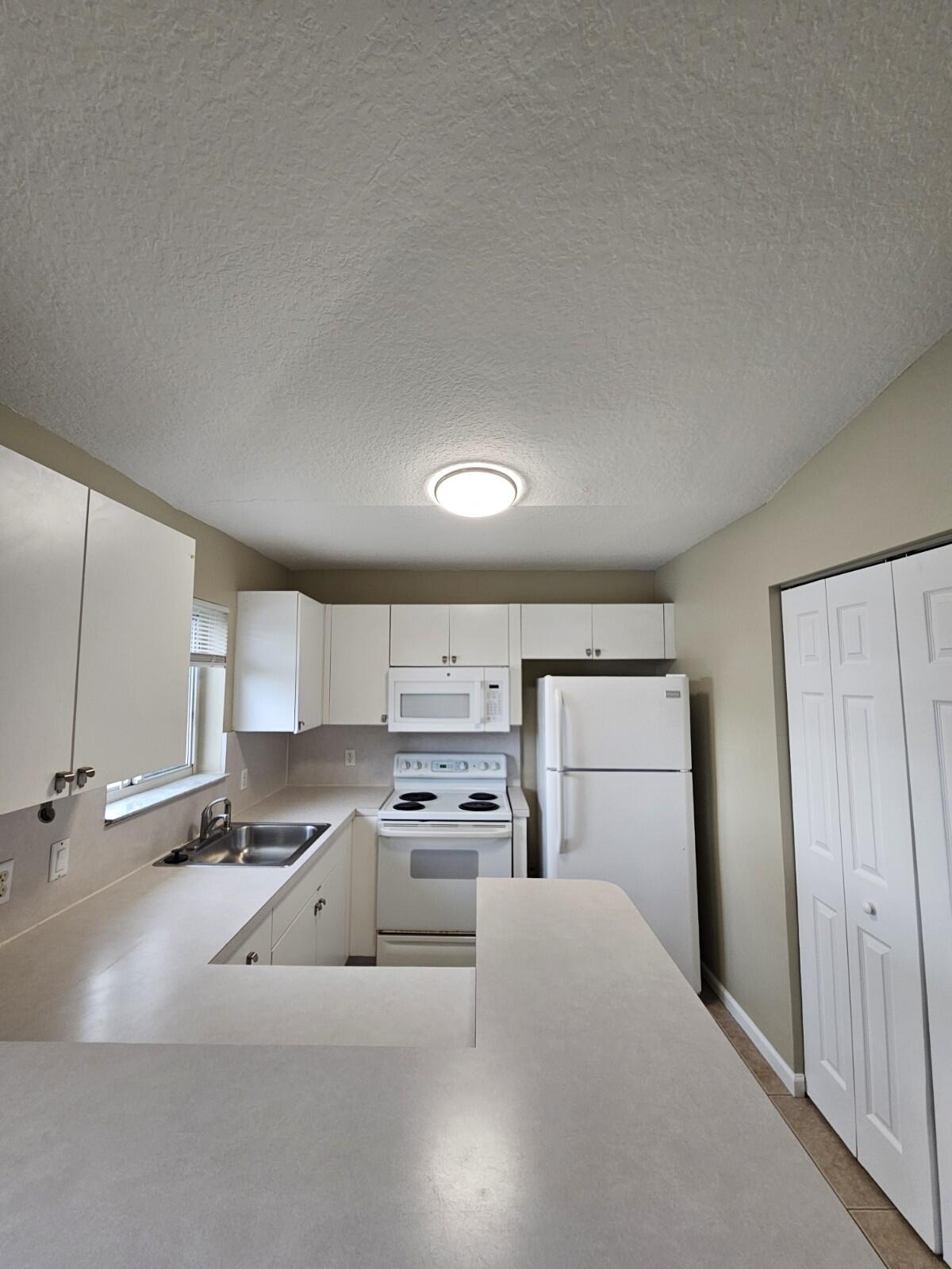 3490 Briar Bay Boulevard, Unit 206 West Palm Beach, FL 33411 - Photo 12 of 25 a kitchen with stainless steel appliances granite countertop a stove a sink and a refrigerator