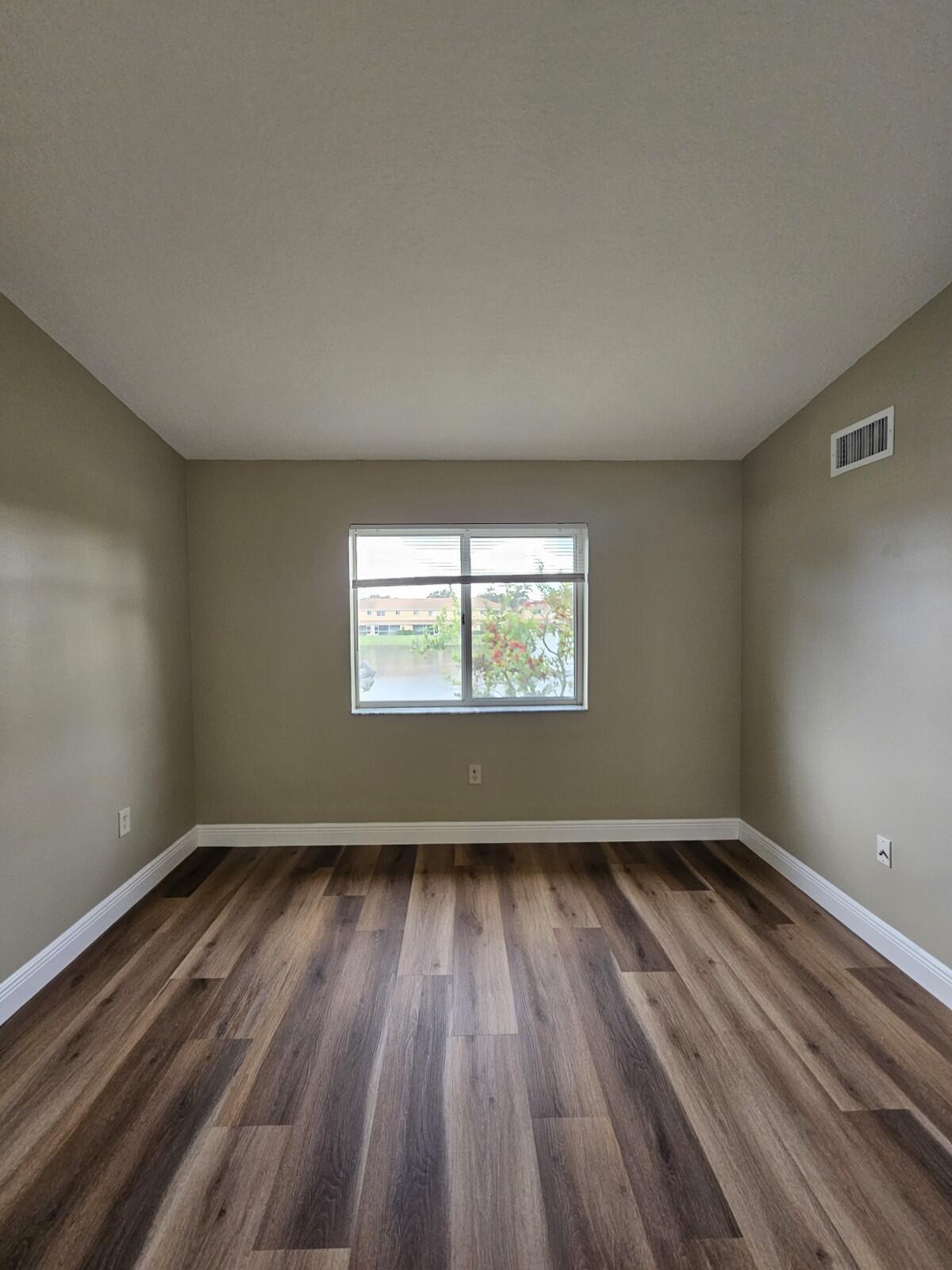 3490 Briar Bay Boulevard, Unit 206 West Palm Beach, FL 33411 - Photo 15 of 25 wooden floor in an empty room with a window