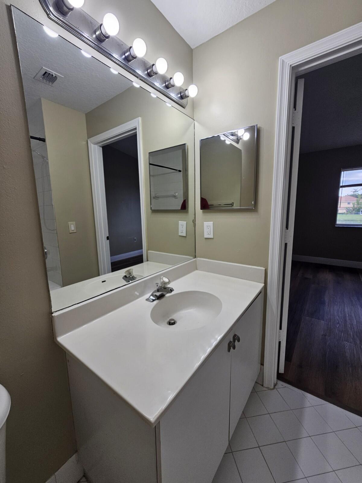 3490 Briar Bay Boulevard, Unit 206 West Palm Beach, FL 33411 - Photo 23 of 25 a bathroom with a sink and a mirror