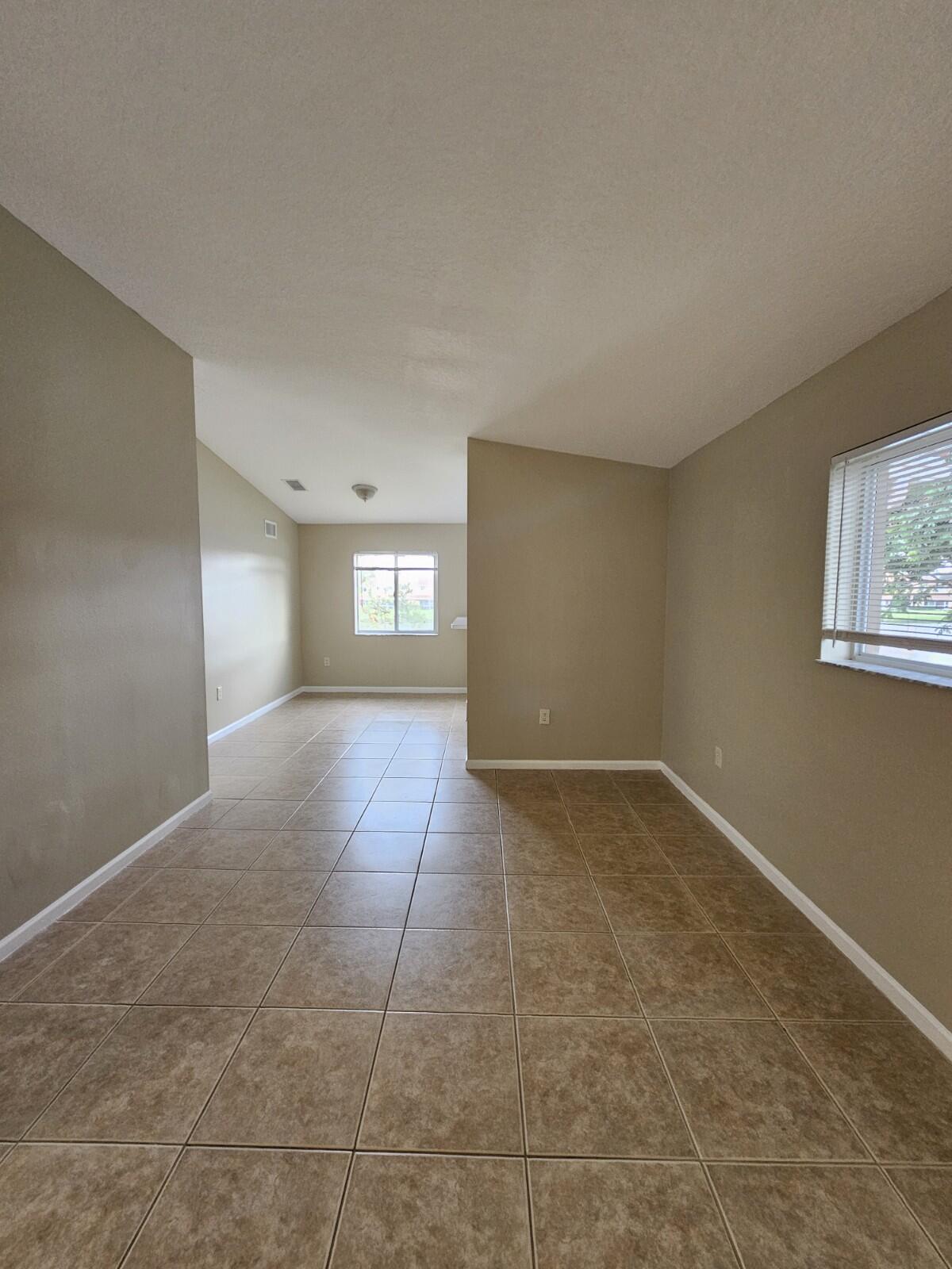3490 Briar Bay Boulevard, Unit 206 West Palm Beach, FL 33411 - Photo 4 of 25 a view of empty room with window and wooden floor