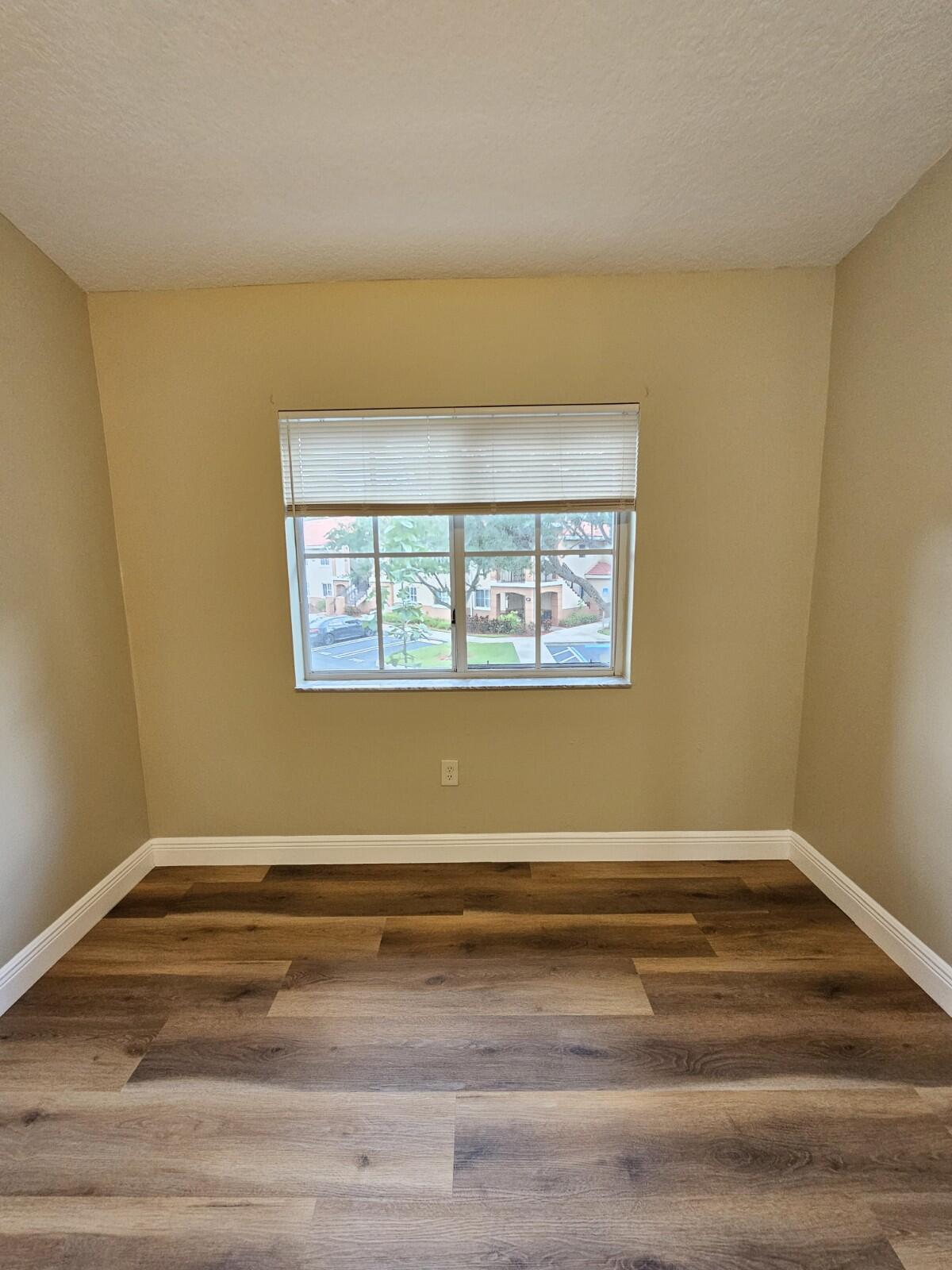 3490 Briar Bay Boulevard, Unit 206 West Palm Beach, FL 33411 - Photo 6 of 25 a view of a room with wooden floor and a window