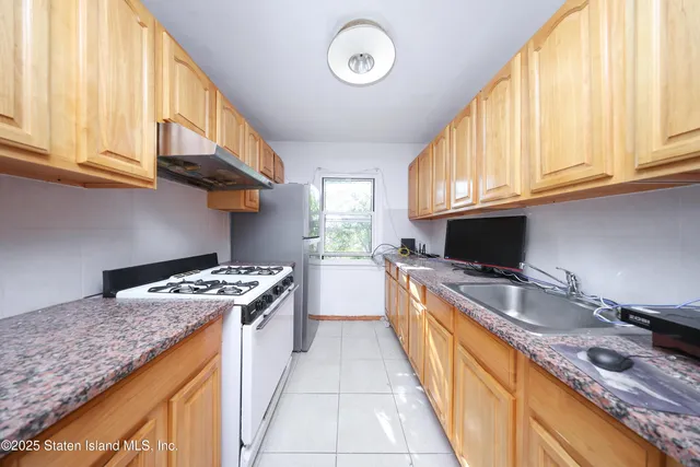 a kitchen with granite countertop stainless steel appliances a stove sink and cabinets