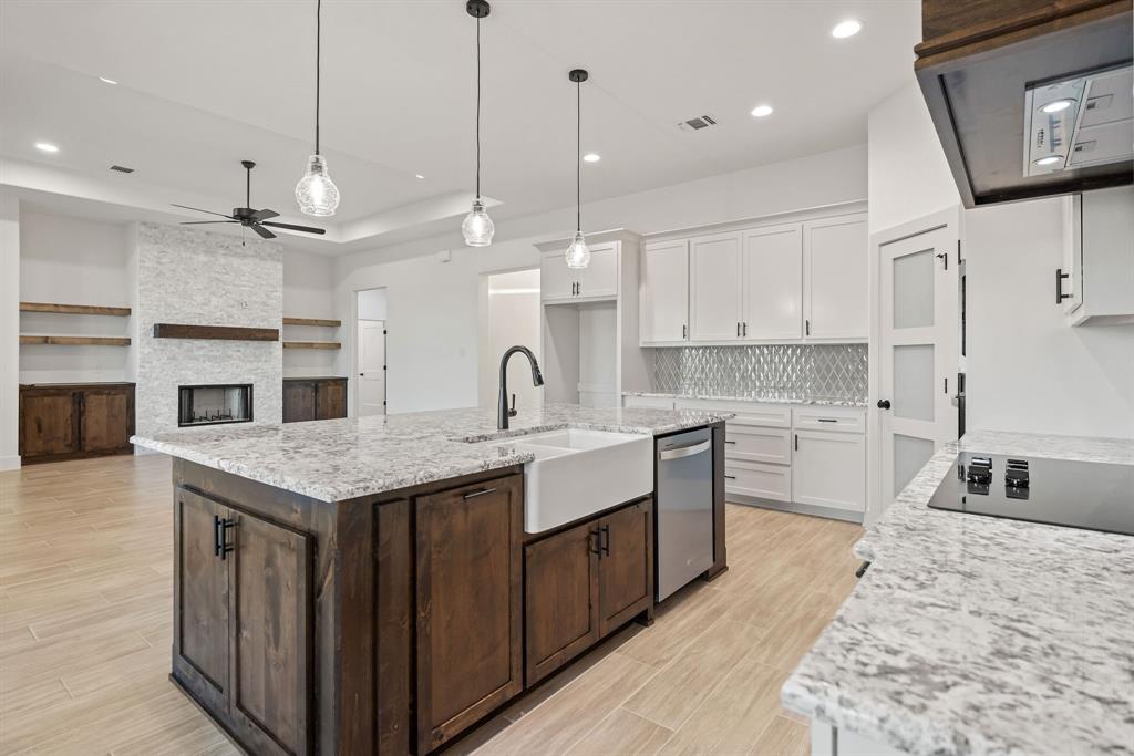 8017 Rnch Vw Place Springtown, TX 76082 - Photo 6 of 18 Open-concept living space featuring a central kitchen island with a farmhouse sink, stainless steel dishwasher, and pendant lighting