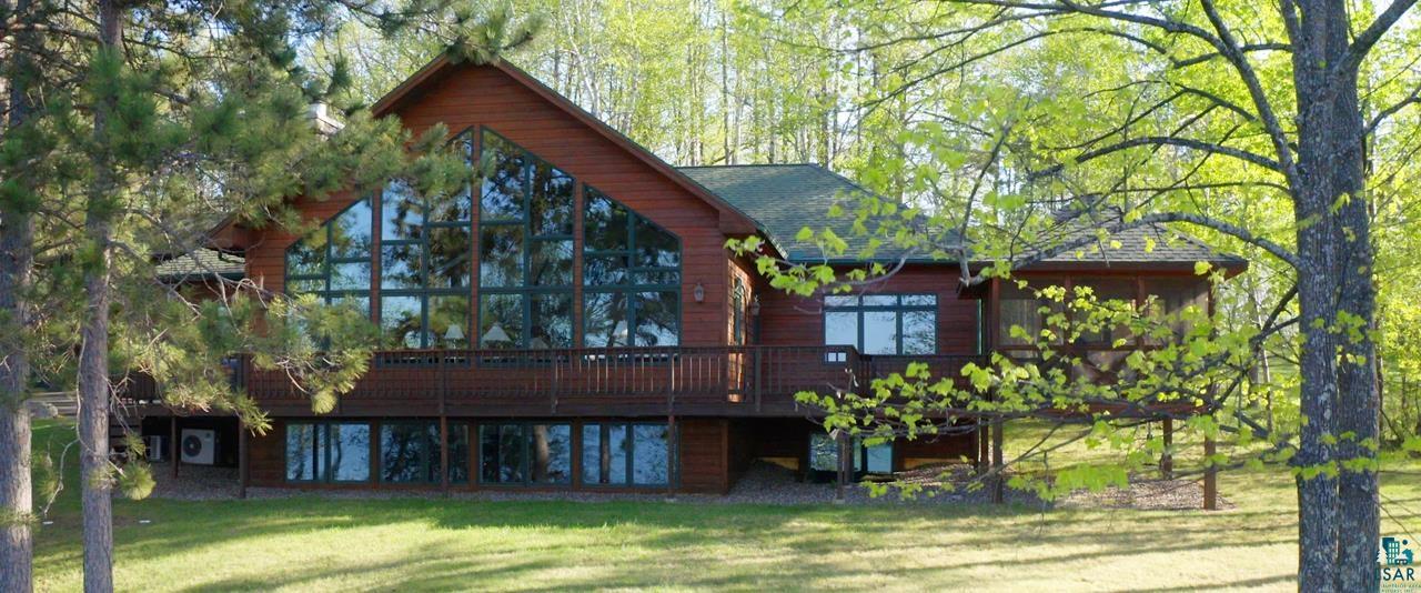 Back of property featuring a yard, roof with shingles, and a deck
