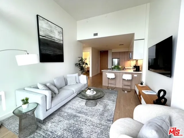a living room with furniture a flat screen tv and kitchen view