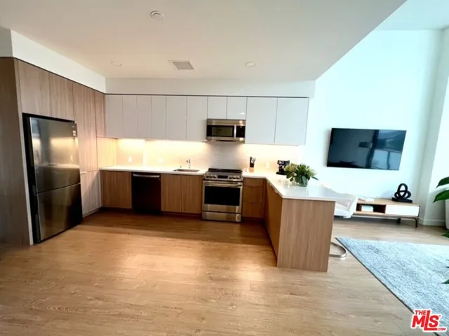 a kitchen with stainless steel appliances kitchen island granite countertop a refrigerator and a stove top oven