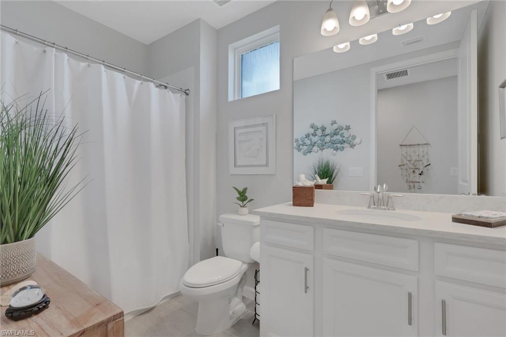 4687 Arboretum Circle, Unit 101 Naples, FL 34112 - Photo 14 of 30 a bathroom with a sink a toilet and a mirror