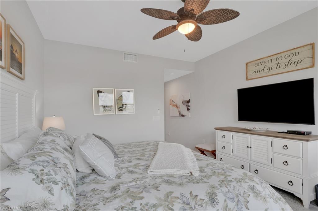 4687 Arboretum Circle, Unit 101 Naples, FL 34112 - Photo 17 of 30 a bedroom with a bed and a flat screen tv