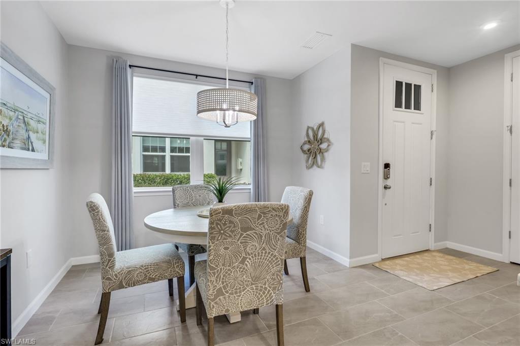 4687 Arboretum Circle, Unit 101 Naples, FL 34112 - Photo 4 of 30 a dining room with furniture a chandelier and window
