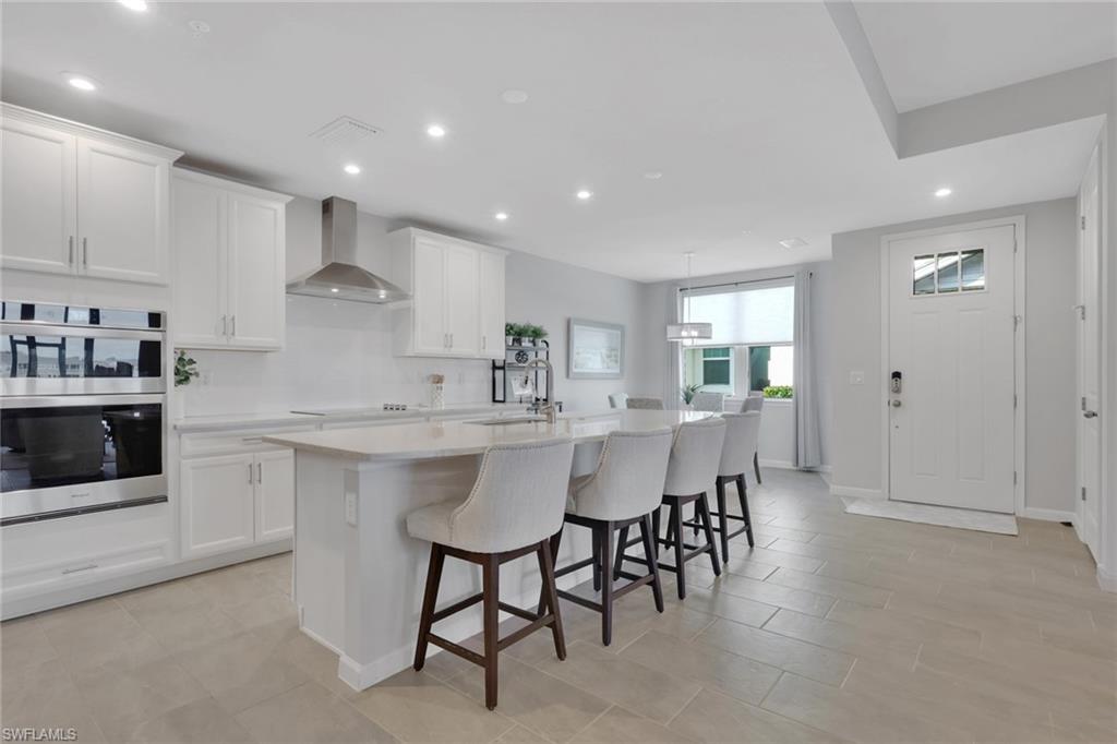 4687 Arboretum Circle, Unit 101 Naples, FL 34112 - Photo 6 of 30 a kitchen with a sink and chairs