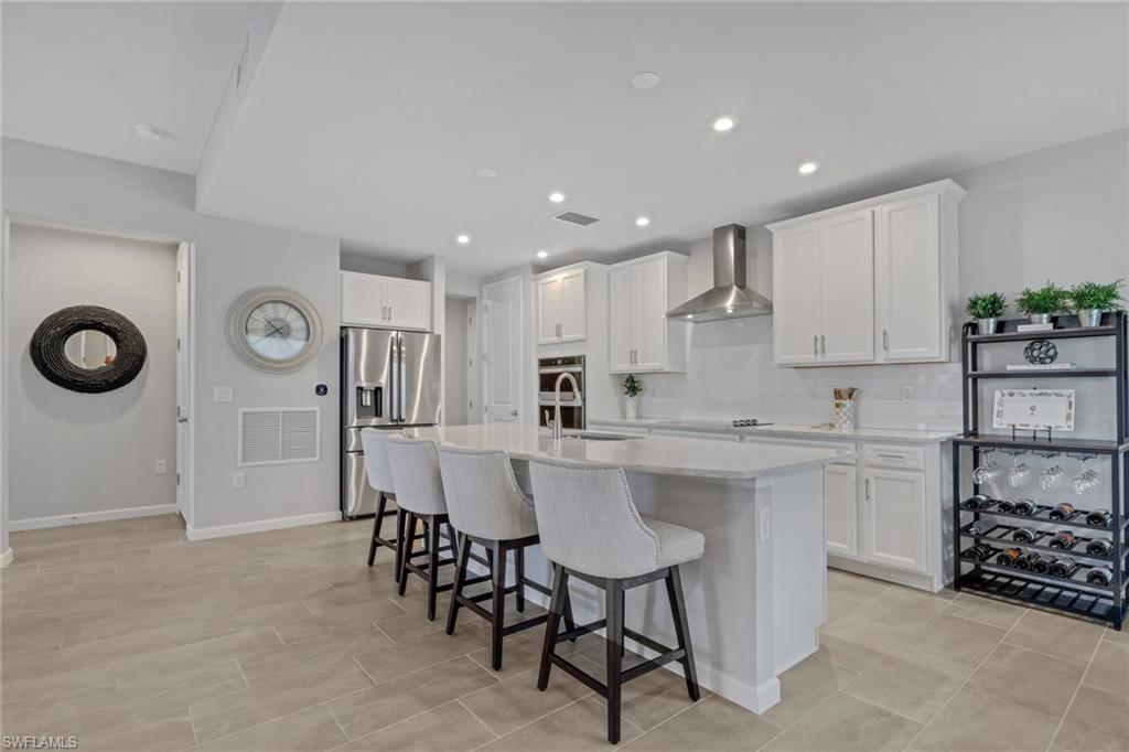 4687 Arboretum Circle, Unit 101 Naples, FL 34112 - Photo 7 of 30 a kitchen with a dining table chairs cabinets and stainless steel appliances