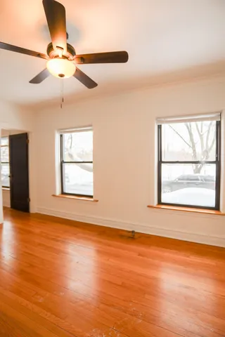an empty room with wooden floor fan and windows
