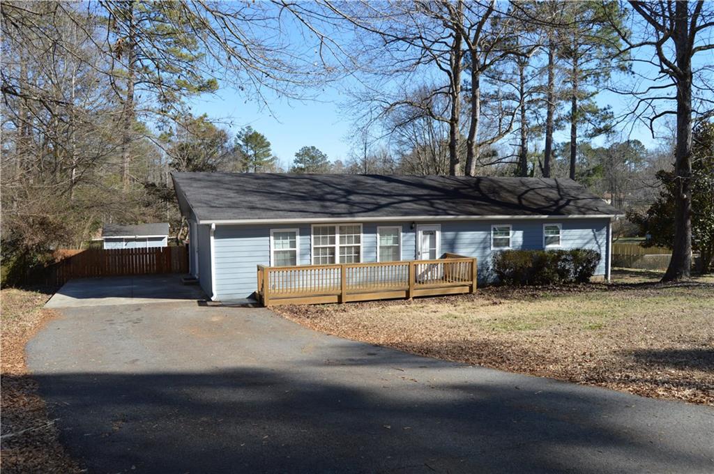 Front of the home with paved driveway and carport
