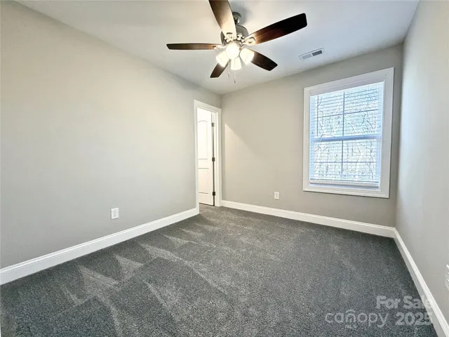 an empty room with windows and ceiling fan