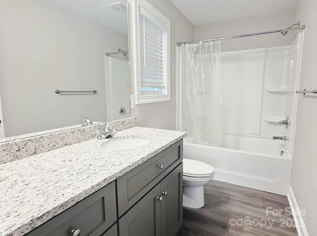 a bathroom with a granite countertop sink a toilet and shower