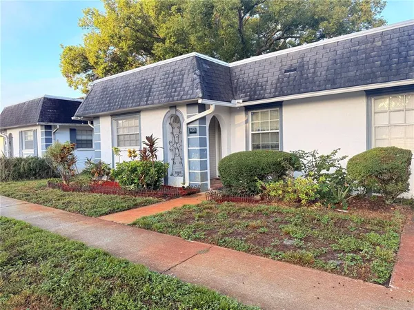 a front view of a house with a yard and potted plants