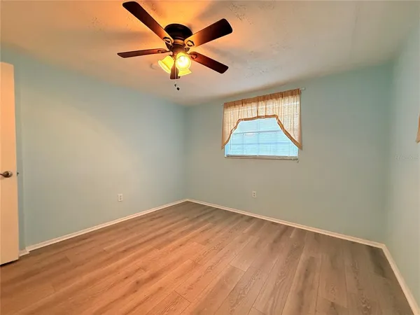 an empty room with a window and a ceiling fan