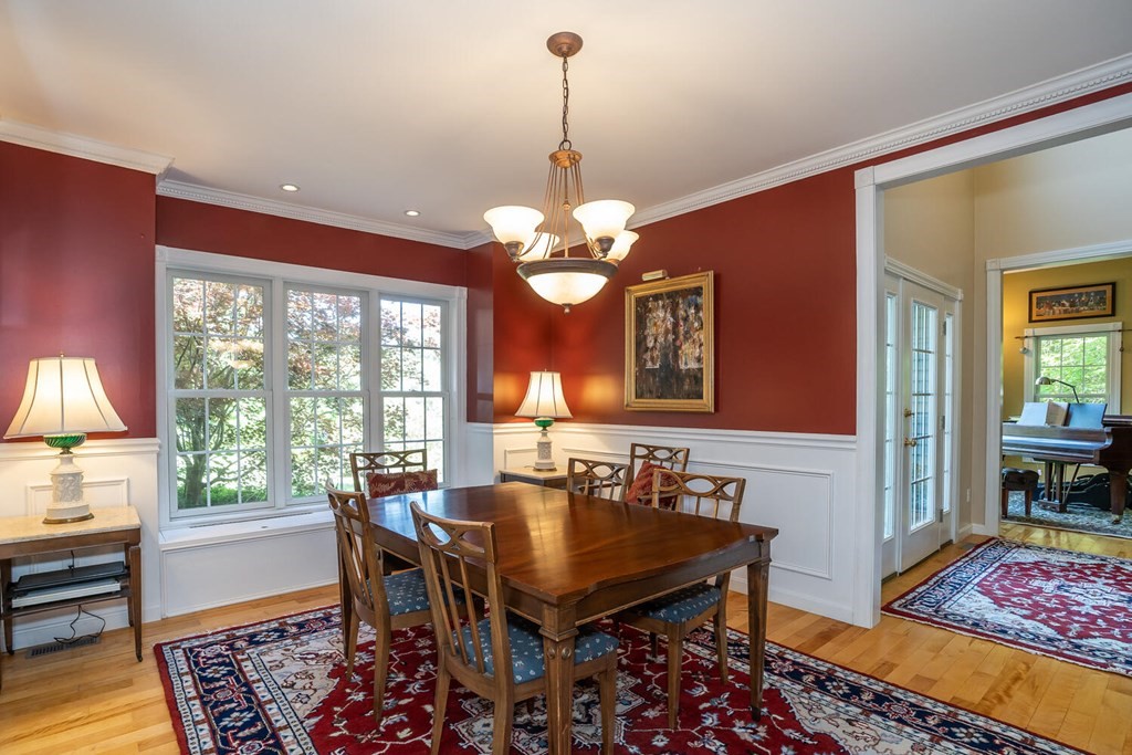 150 East Leverett Road Amherst, MA 01002 - Photo 19 of 42 a dining room with wooden floor a chandelier a wooden table and chairs