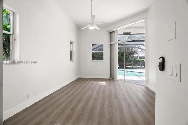 a view of an empty room with wooden floor and a window