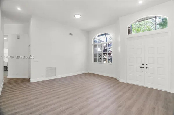 an empty room with wooden floor and windows