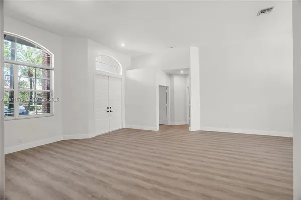 a view of an empty room with wooden floor and a window
