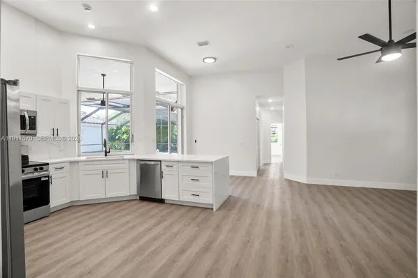 a large kitchen with a window wooden cabinets and stainless steel appliances