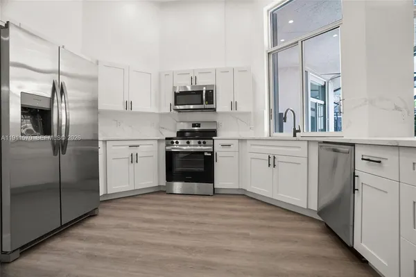 a kitchen with stainless steel appliances granite countertop a stove top oven a sink and a refrigerator