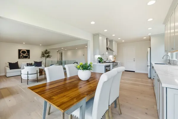 a kitchen with stainless steel appliances a refrigerator a stove a sink a dining table and chairs