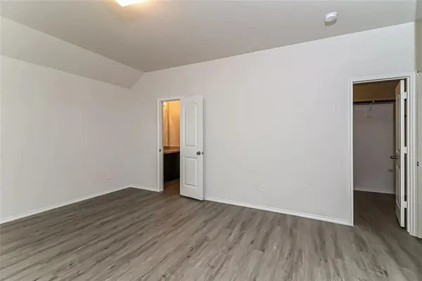 a view of an empty room with wooden floor and closet