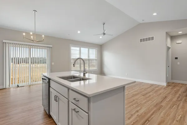 a kitchen with stainless steel appliances granite countertop a sink a stove and a wooden floor