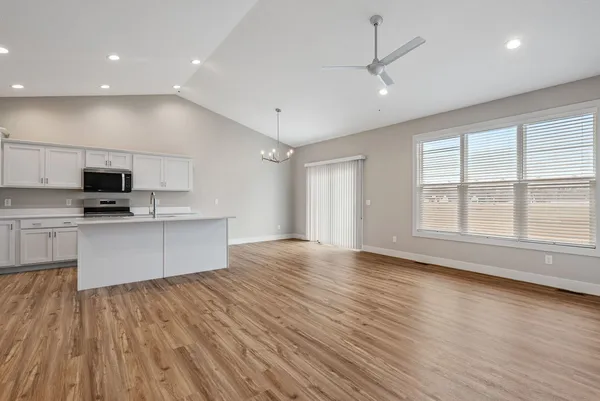 a large kitchen with stainless steel appliances a large window a oven and white cabinets