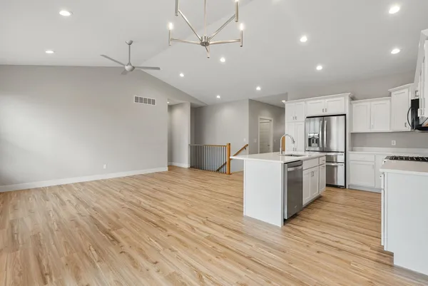 a large kitchen with a large counter top a sink stainless steel appliances and cabinets