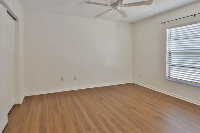 a view of an empty room with wooden floor and closet