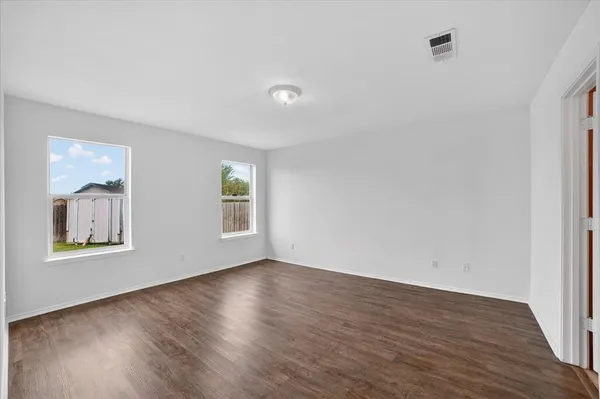 a view of an empty room with wooden floor and a window
