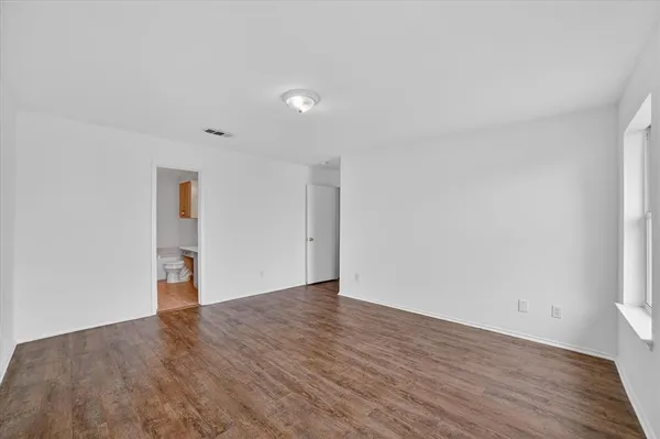 an empty room with wooden floor & windows