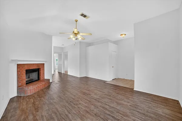 a view of an empty room with wooden floor and a fireplace