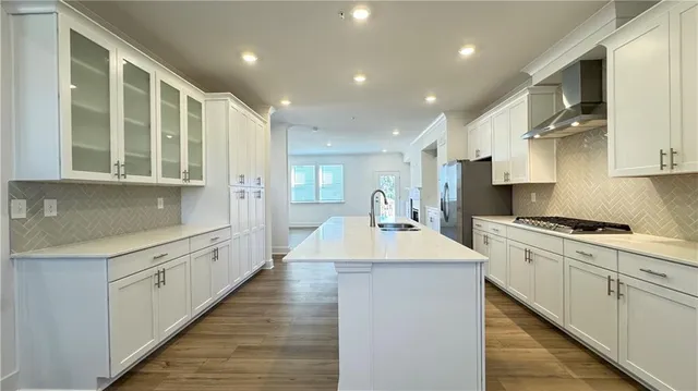 a large kitchen with kitchen island a sink a counter top space a stove and a refrigerator