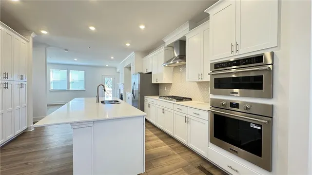 a hallway with white cabinets and wooden floors